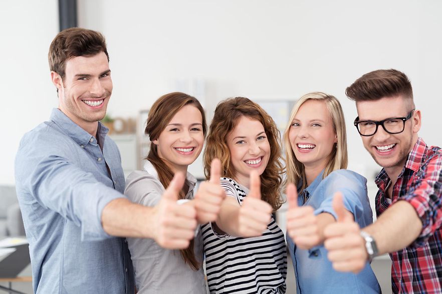 Gruppenfoto: Fünf junge Menschen lächeln in die Kamera und zeigen den Daumen hoch